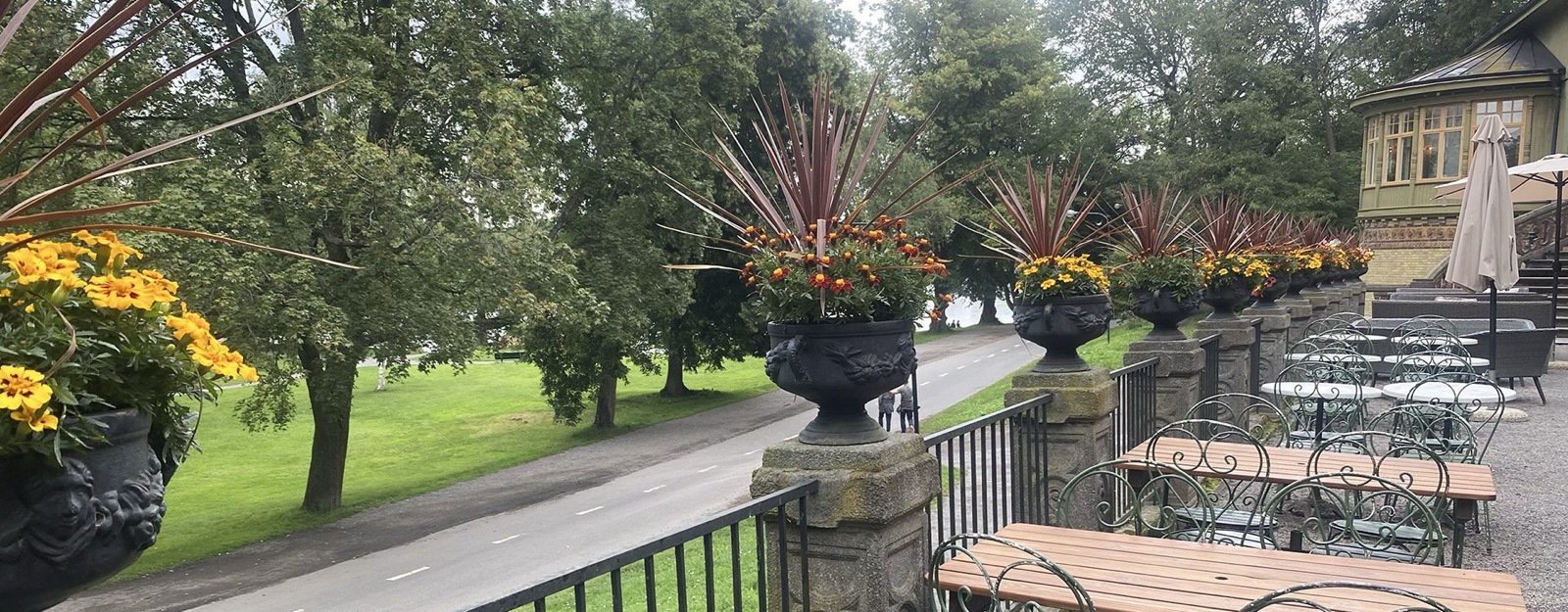 Terrassen med blomsterurnor, långbord och utsikt över parken