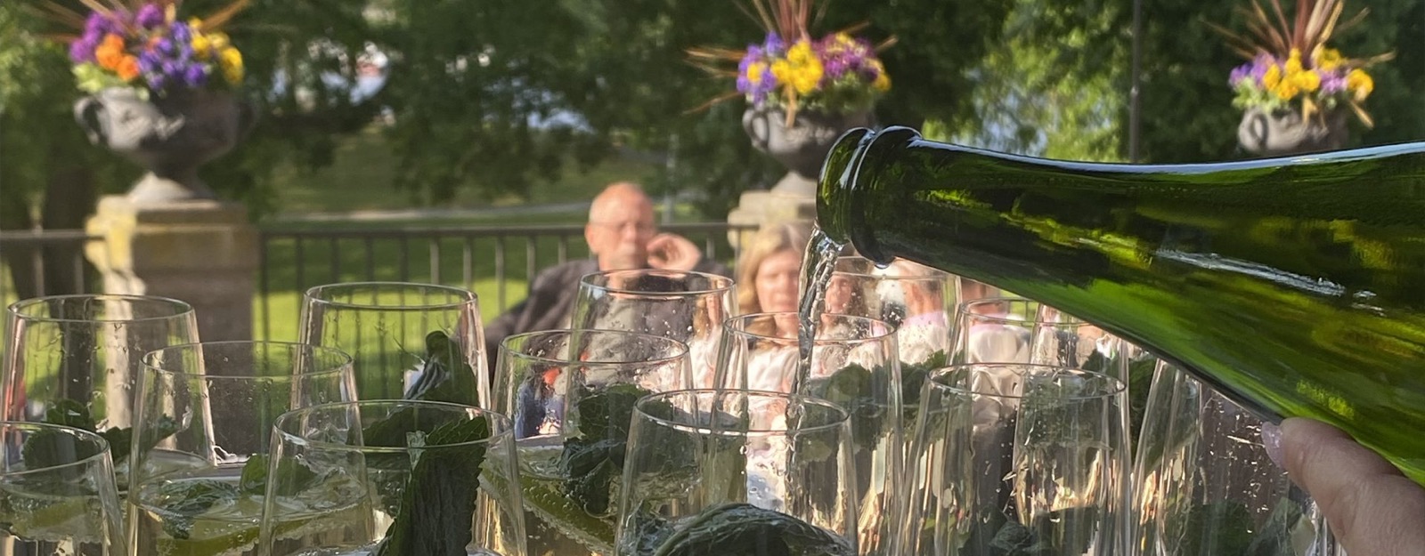 Vin hälls upp vid ett långbord med gäster på terrassen