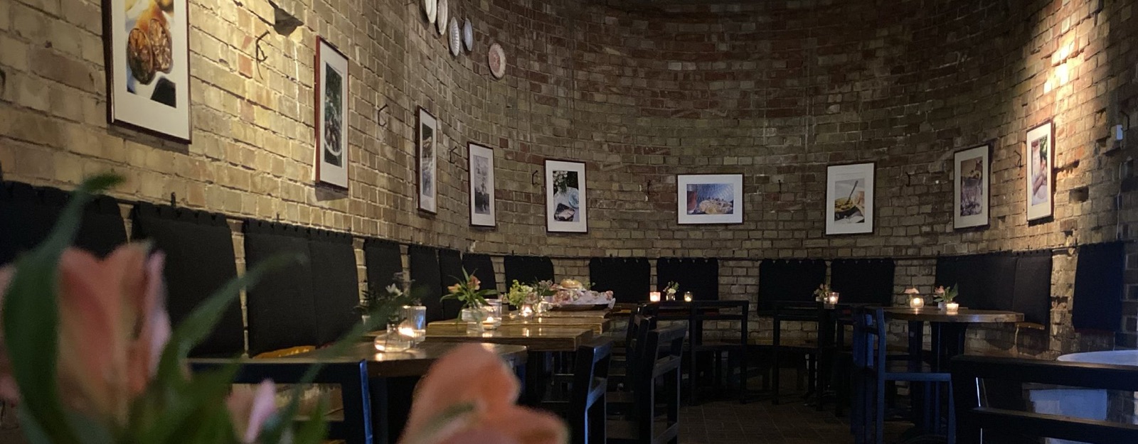 Restaurangens inre med tegelvalv, tända ljus och dukade bord